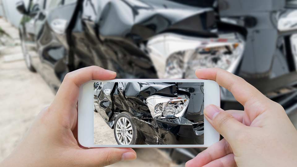 Unfallwagenankauf Preetz: Unfallschaden an einem Auto wird mit dem Smartphone fotografiert.